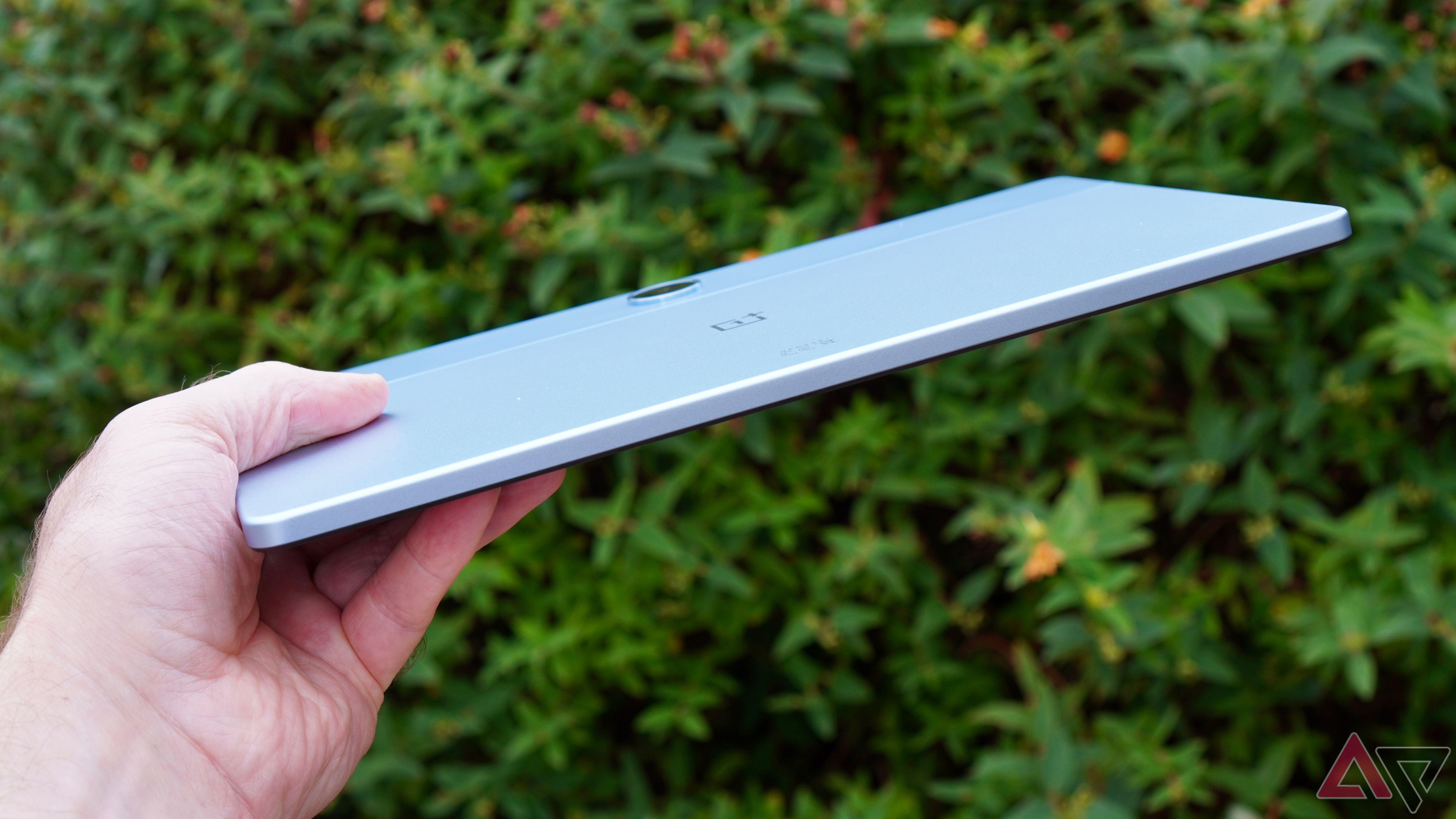 A person holding the OnePlus Pad Lite, showing the side of the chassis