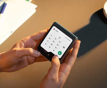 A hand holding a Google Pixel covered by a red cloth with 'AI' written behind, and some AI sparkles around.