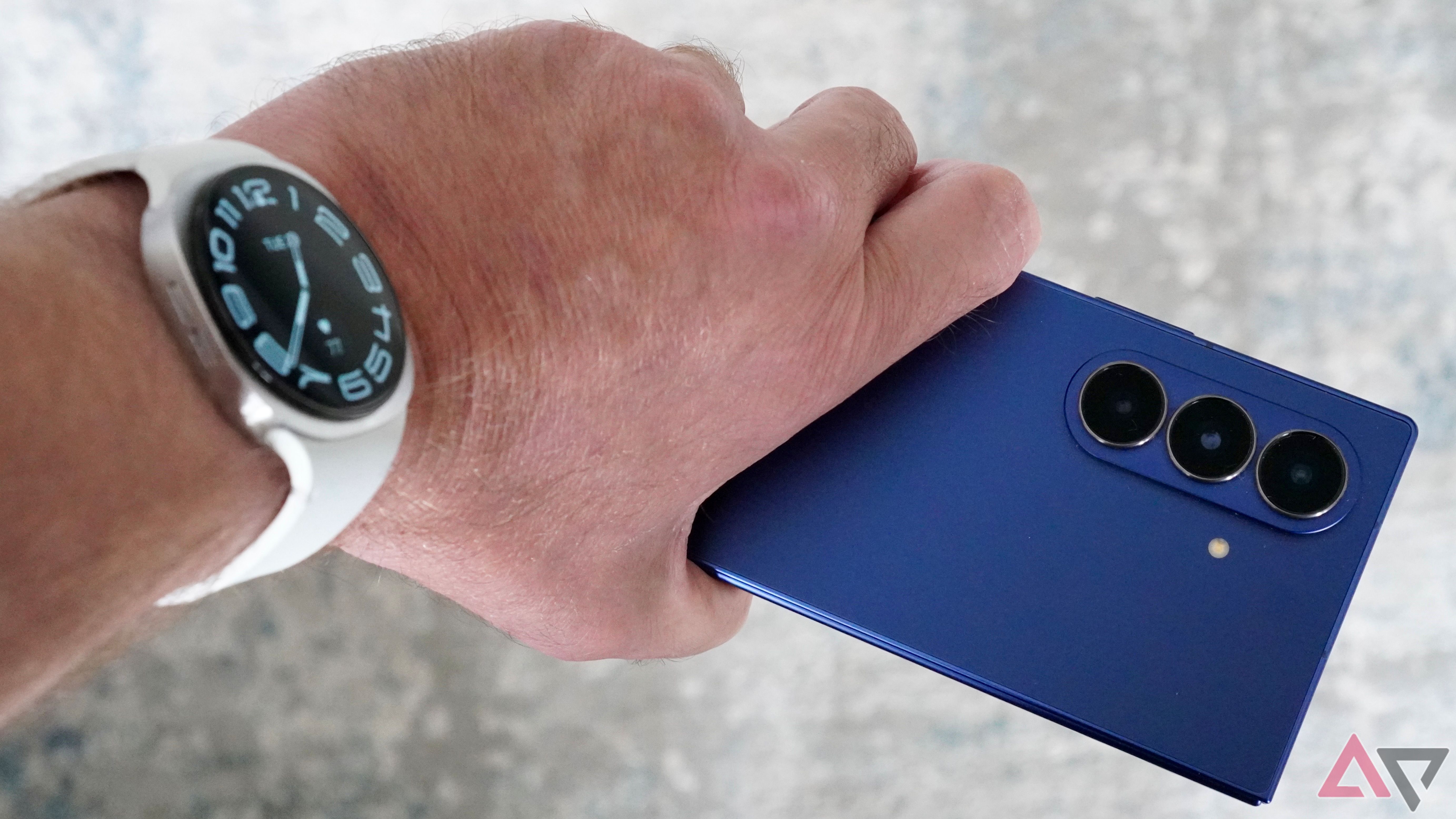 A person wearing the Samsung Galaxy Watch 8 and holding the Galaxy Z Fold 7