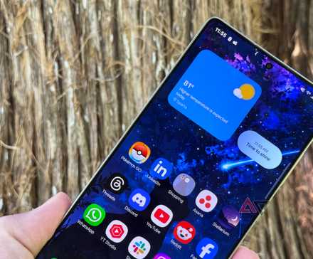 A Samsung Galaxy A25 with a One UI 6 home screen while sitting on a brown table